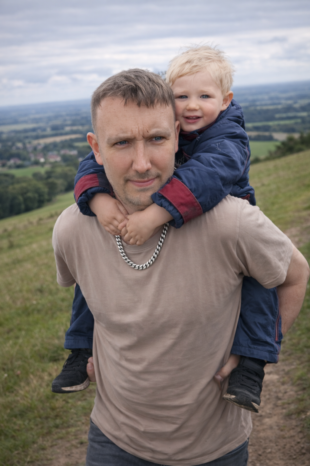 Matthew carrying his young son on his shoulders on a hillside